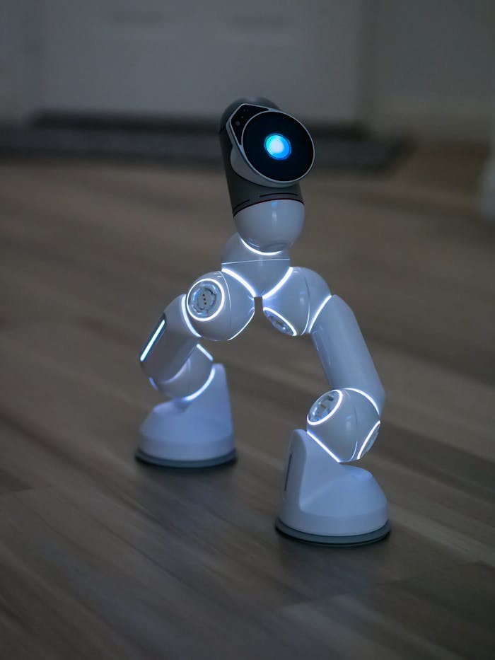 services-02 Close-up of a futuristic AI robot with illuminated joints on a wooden floor.