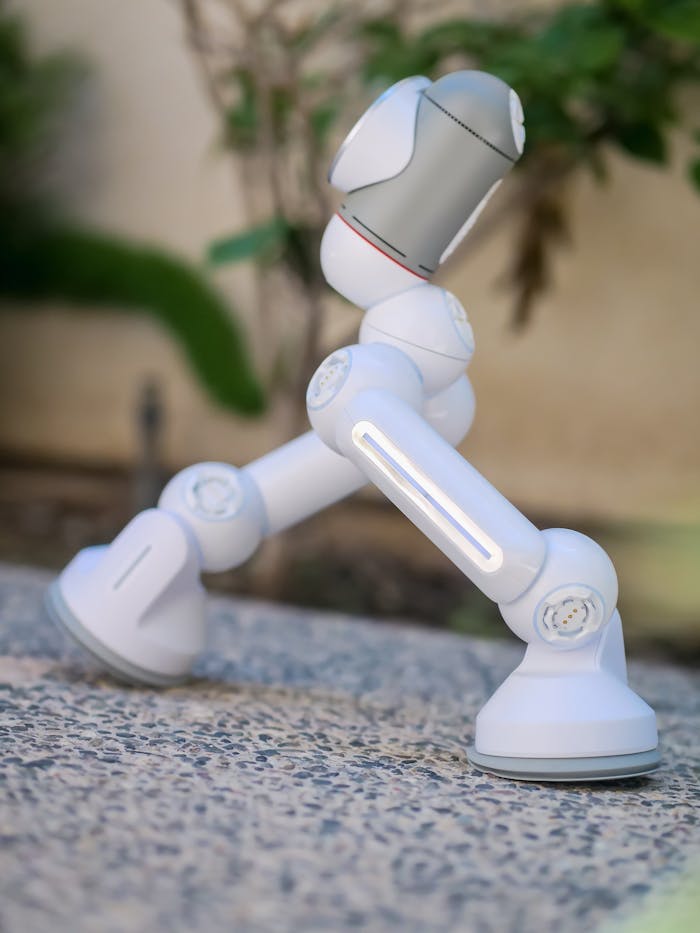 Close-up of a modern white robot with advanced design standing outdoors on pebbled ground.